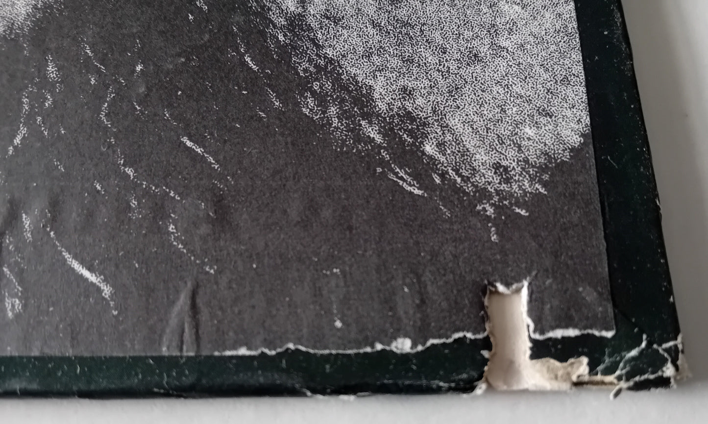 Close-up of an album cover with small corner tears and a cut groove.