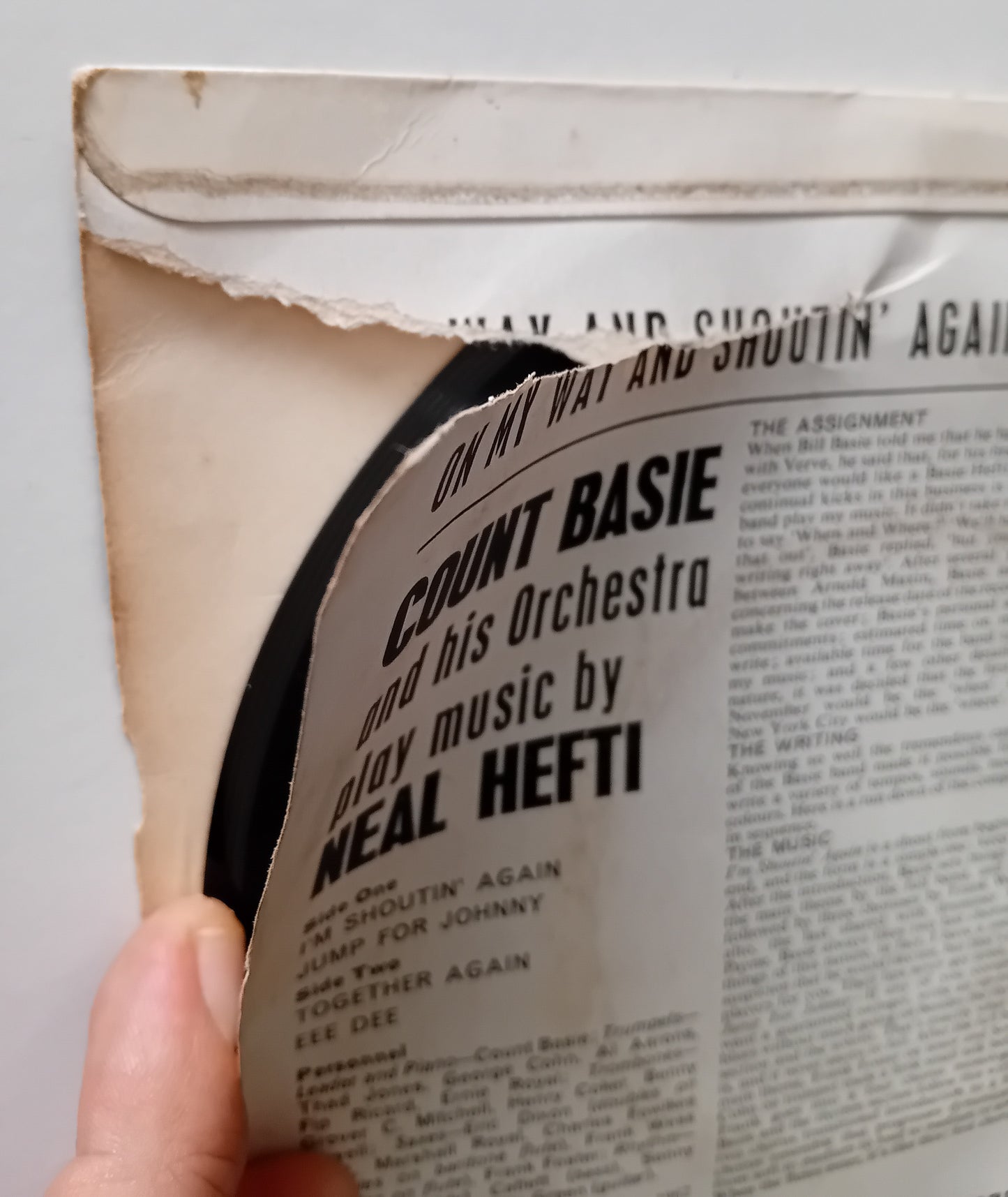 Close-up of a vintage record sleeve with a tear and a hand holding it.