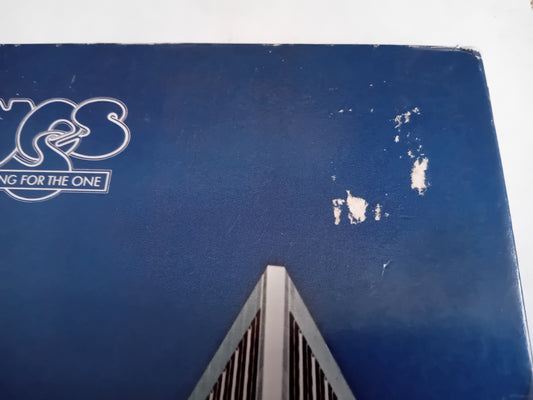 A close-up of a blue sleeve with a worn logo on the left and small surface tears.