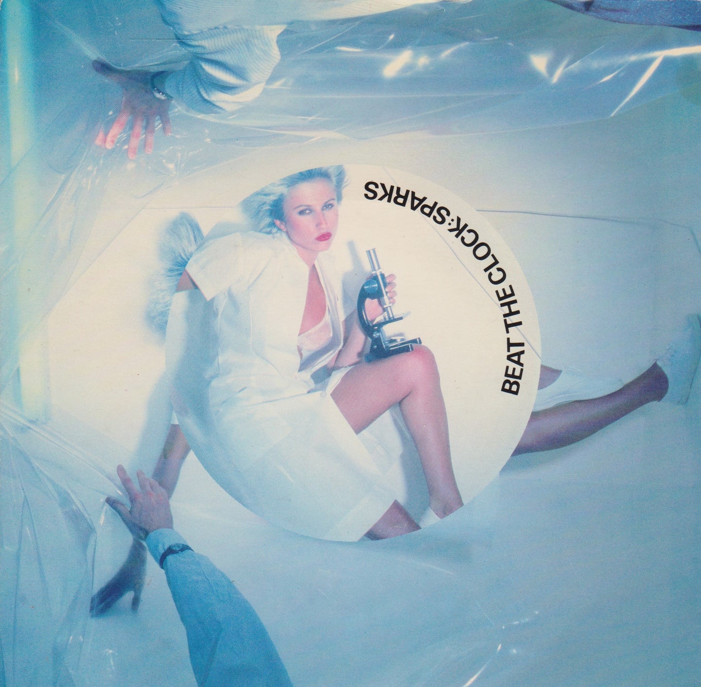 A vinyl record sleeve featuring a monochrome image of a person sitting in a chair with text overlay related to the Sparks band and the single 'Beat The Clock'.
