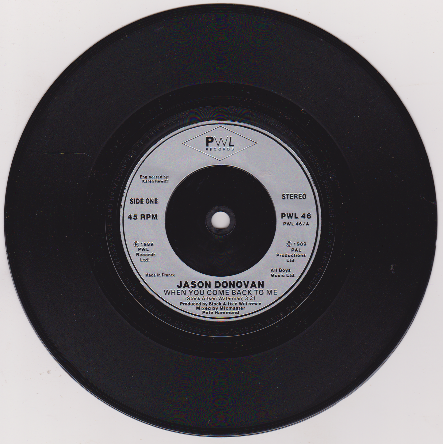 Black vinyl record with white label featuring 'PWL' records on a white background