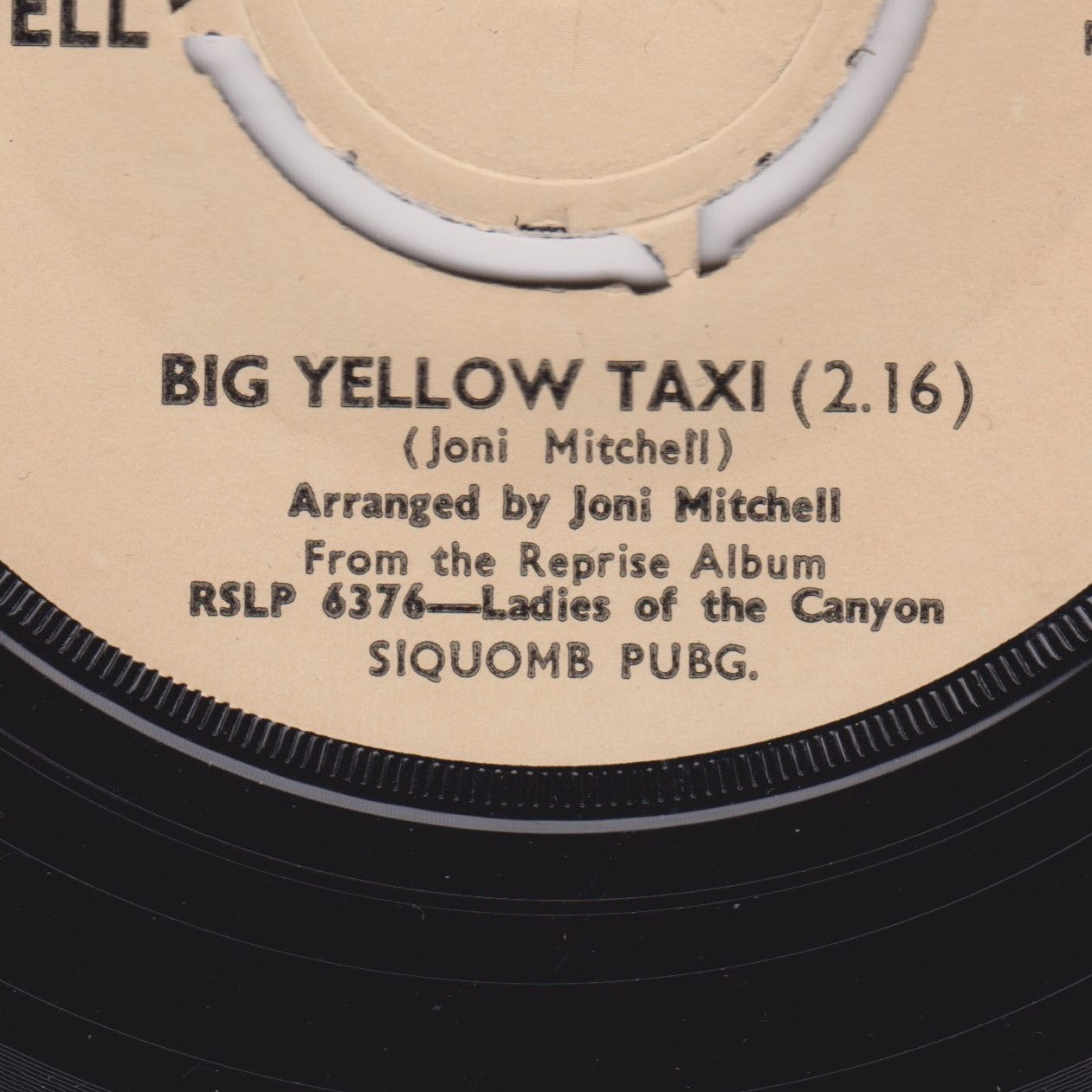 Record label with text 'BIG YELLOW TAXI' by Joni Mitchell on a beige background