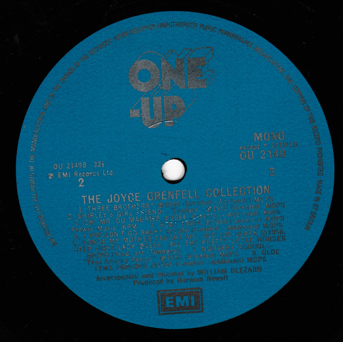 A blue vinyl record label for 'The Joyce Grenfell Collection' on EMI Records, featuring the One-Up series logo and track listings on a black background.