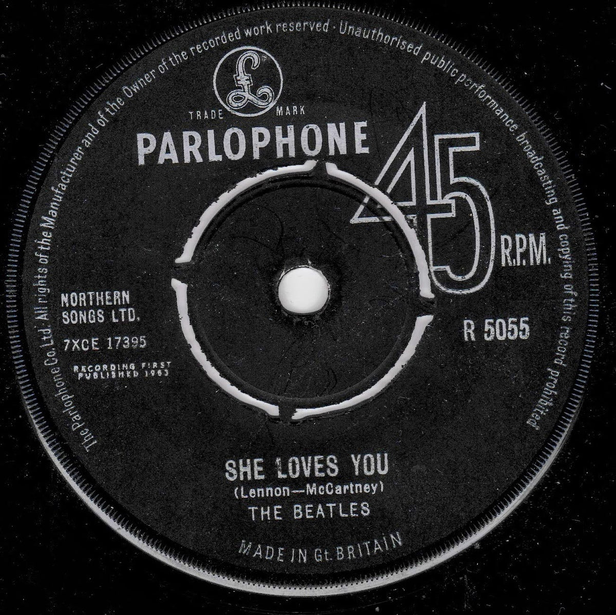 A black 45 RPM vinyl record label for The Beatles' 'She Loves You', featuring the Parlophone logo and white text on a black background.