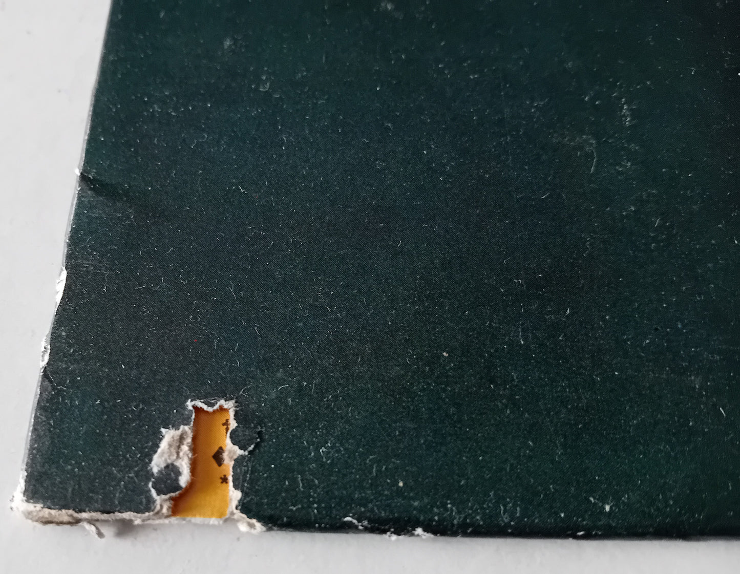 Close-up of a dark green material with a small cutout revealing a lighter interior.