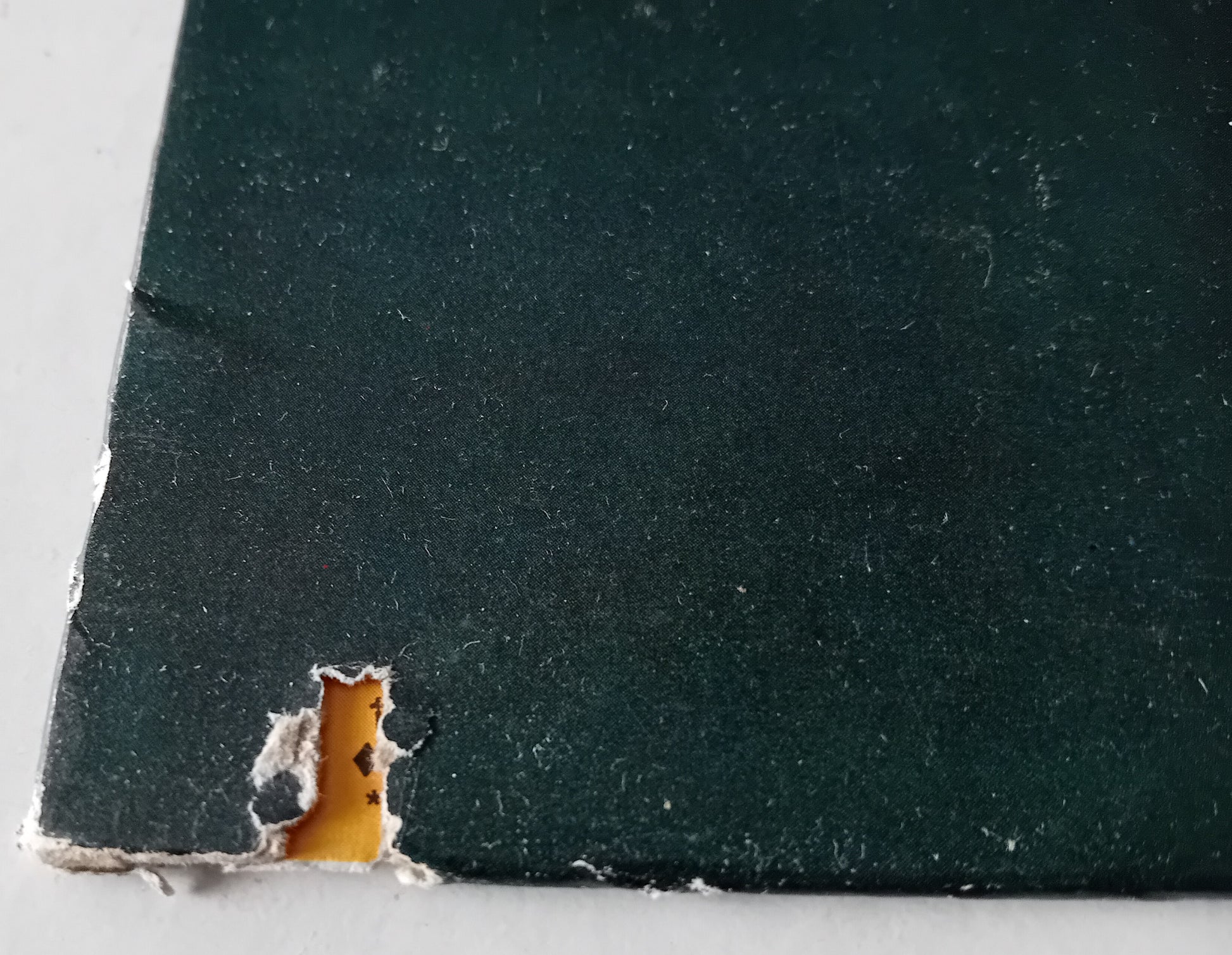Close-up of a dark green material with a small cutout revealing a lighter interior.