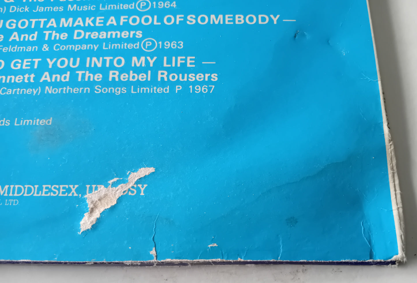 Close-up of a blue record sleeve with text and a tear on the corner.