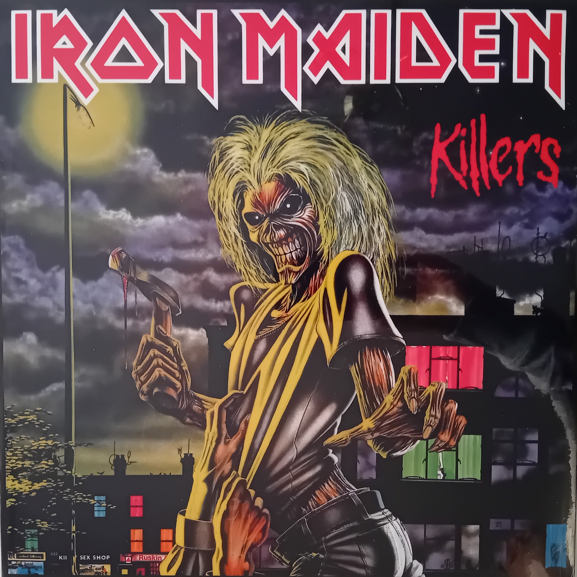Album cover for Iron Maiden's 'Killers' with a dark, moody sky and a character holding a weapon.