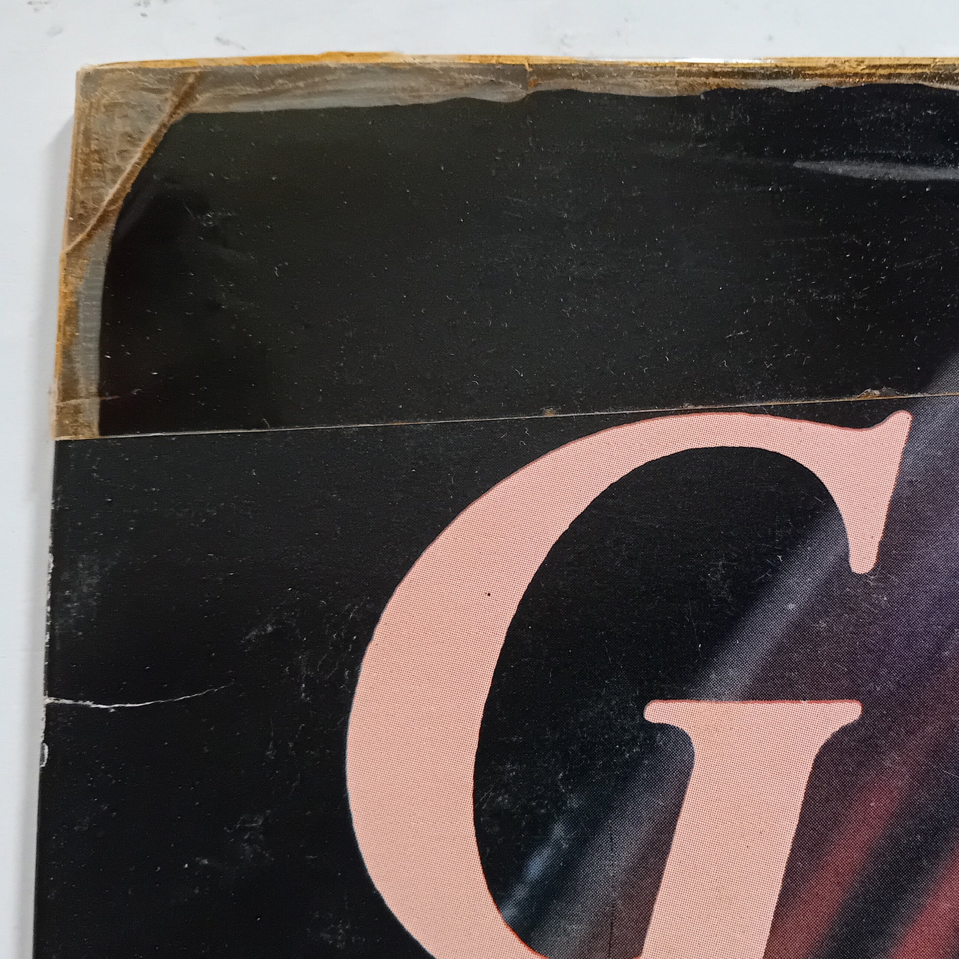 Close-up of a vinyl record with a large pink letter 'G' on a black background.