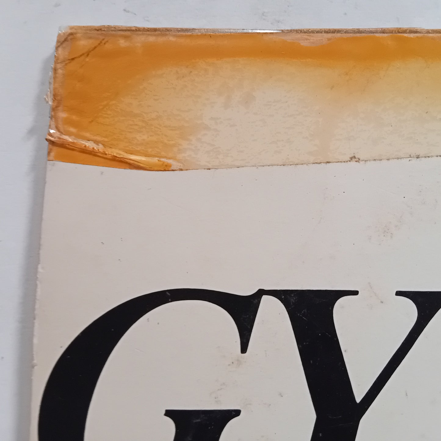 Close-up of an LP cover corner with visible wear and a large black letter 'G' on a white background.