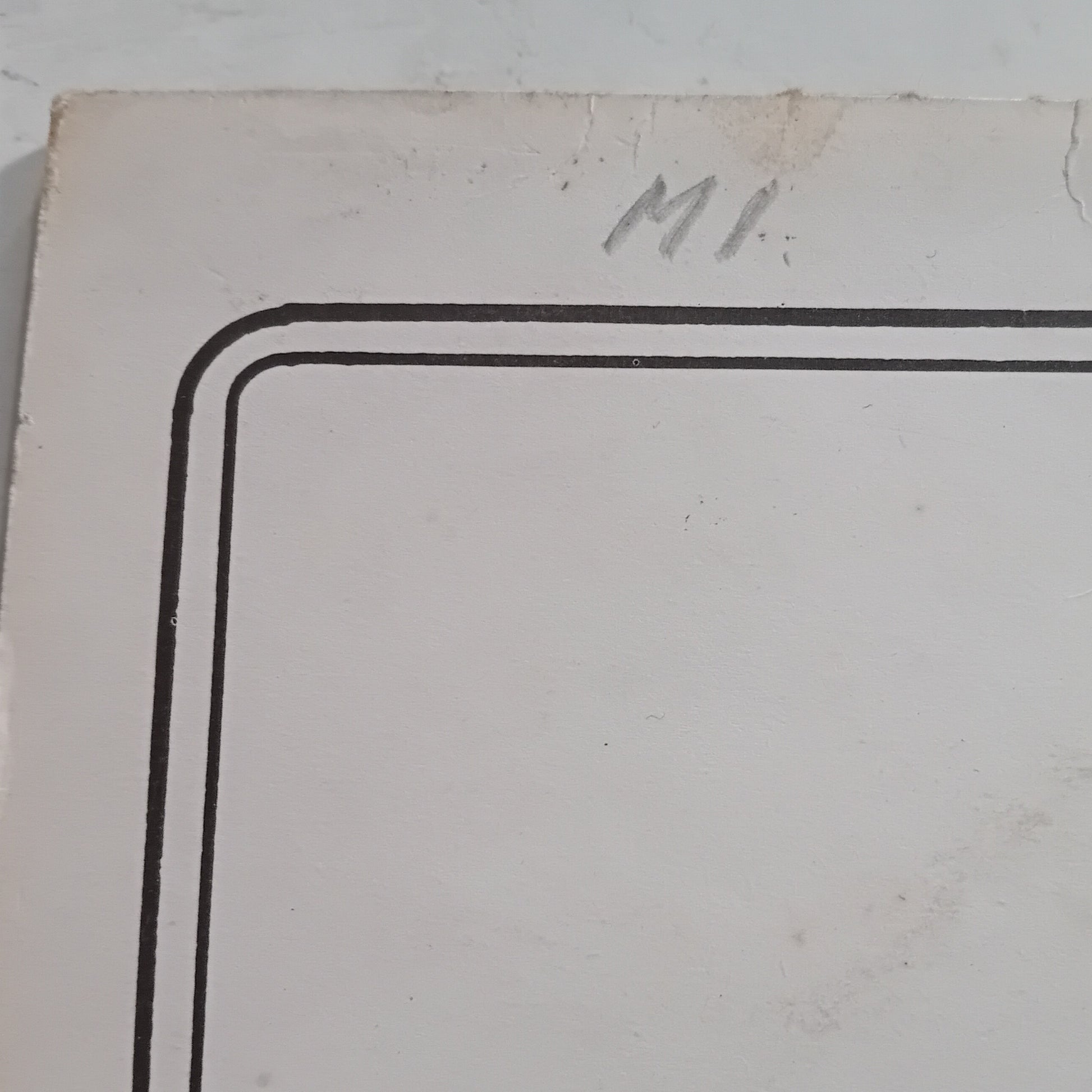 Corner of a white card with black border and 'MI' initials on a light gray background