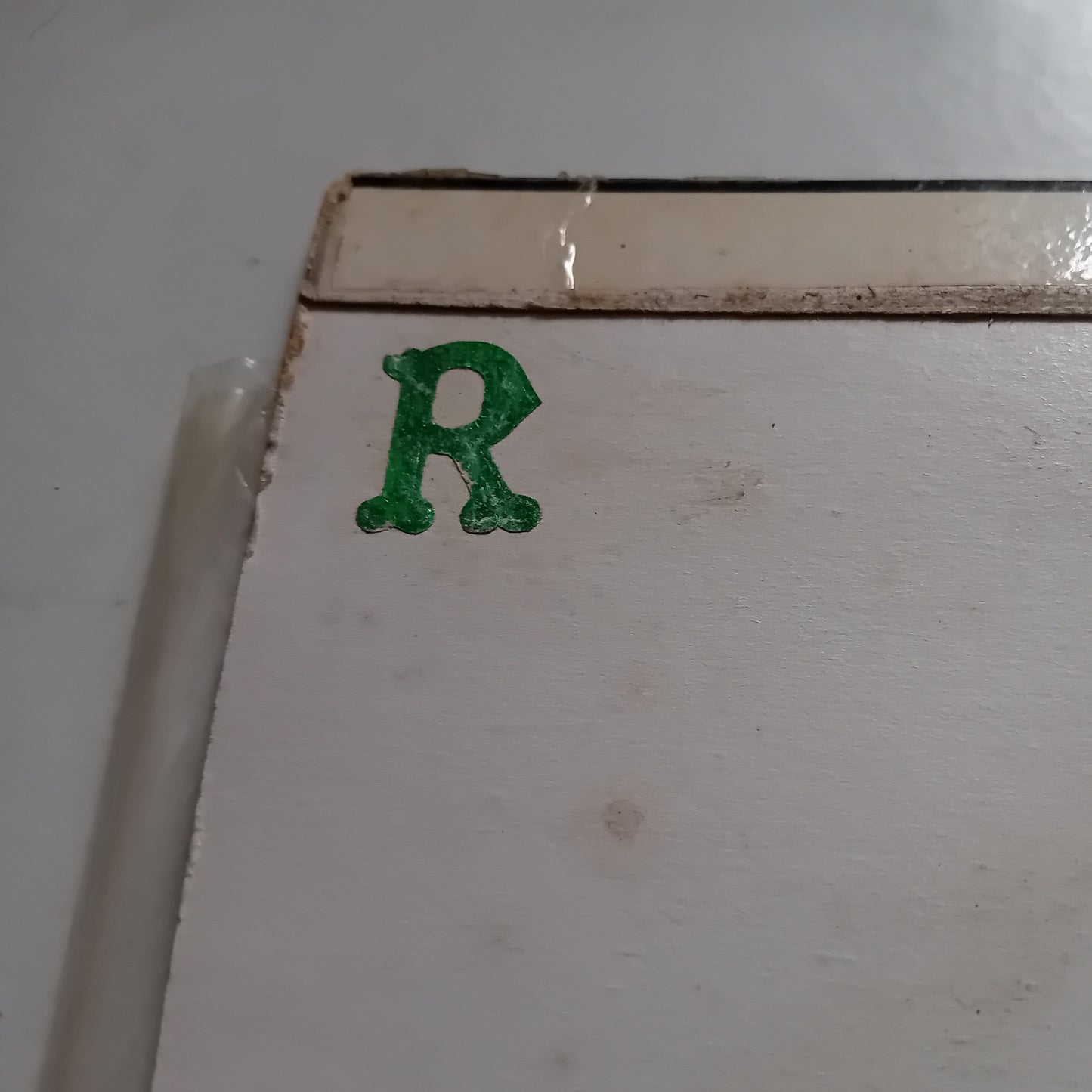 Green letter 'R' sticker on a white surface