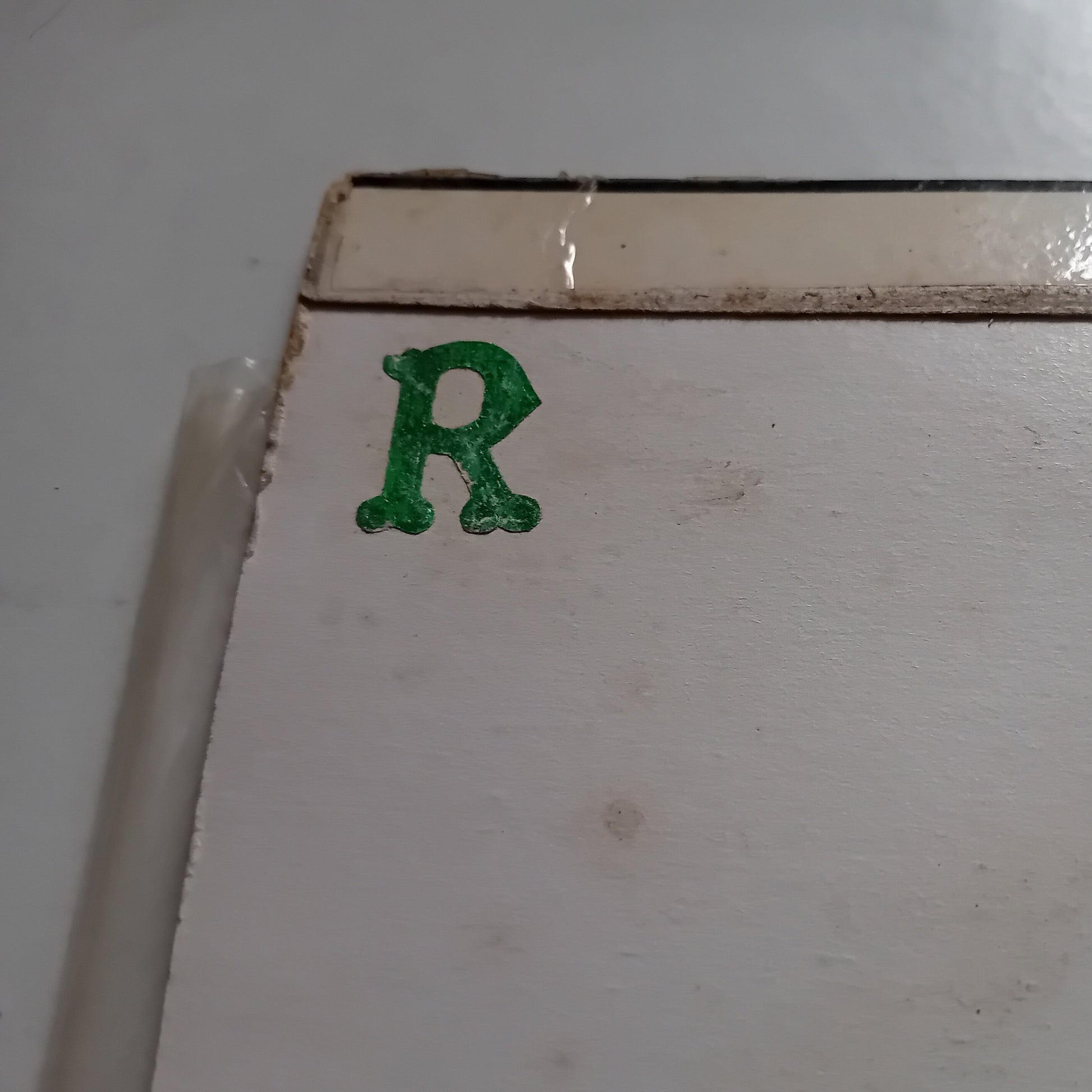 Green letter 'R' sticker on a white surface
