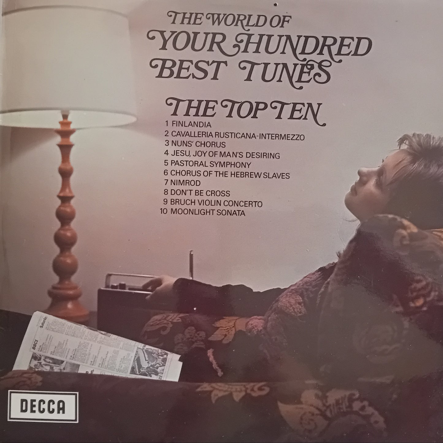 Album cover for 'The World of Your Hundred Best Tunes' by Decca Records with a woman sitting on a couch.