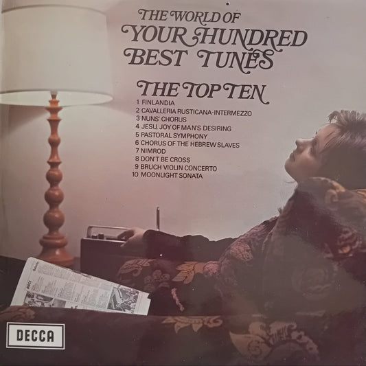 Album cover for 'The World of Your Hundred Best Tunes' by Decca Records with a woman sitting on a couch.