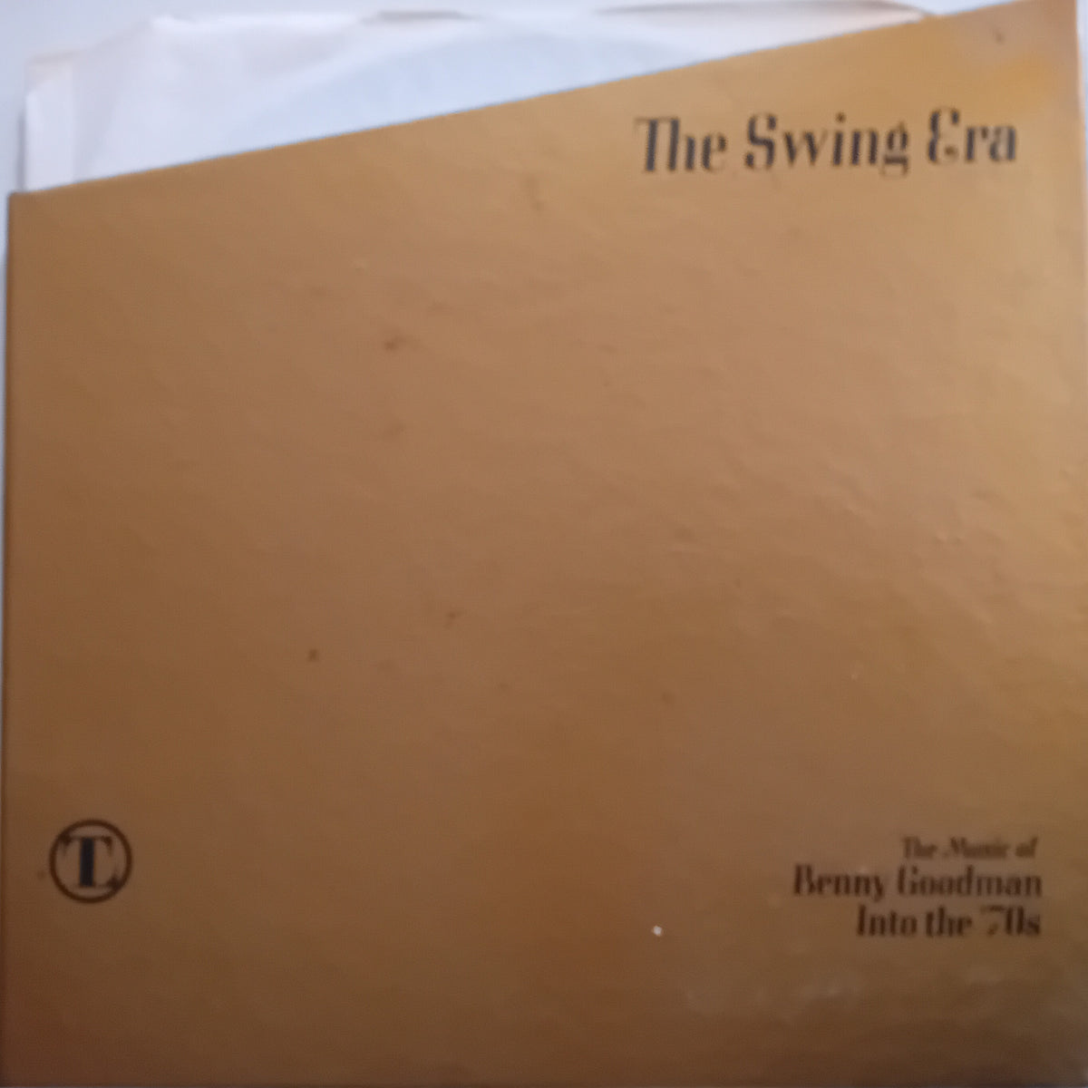 A square tan vinyl record sleeve with black text reading 'The Swing Era' and 'The Music of Benny Goodman Into the 70s,' plus a circular 'L' logo in the lower left, photographed against a white background.