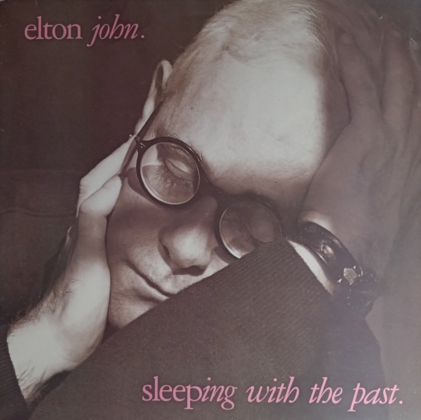 Album cover of 'Sleeping with the Past' by Elton John featuring a close-up of a person wearing glasses.