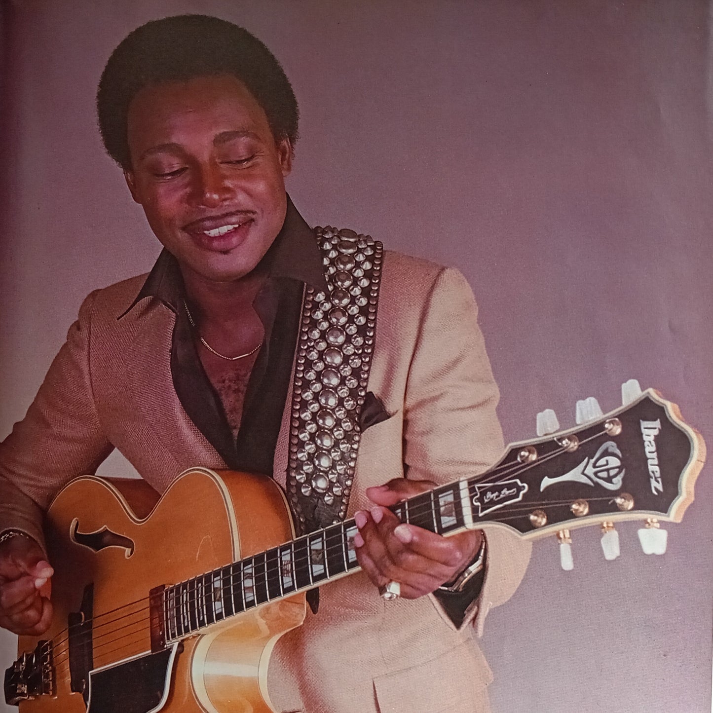 Man playing a guitar against a plain background