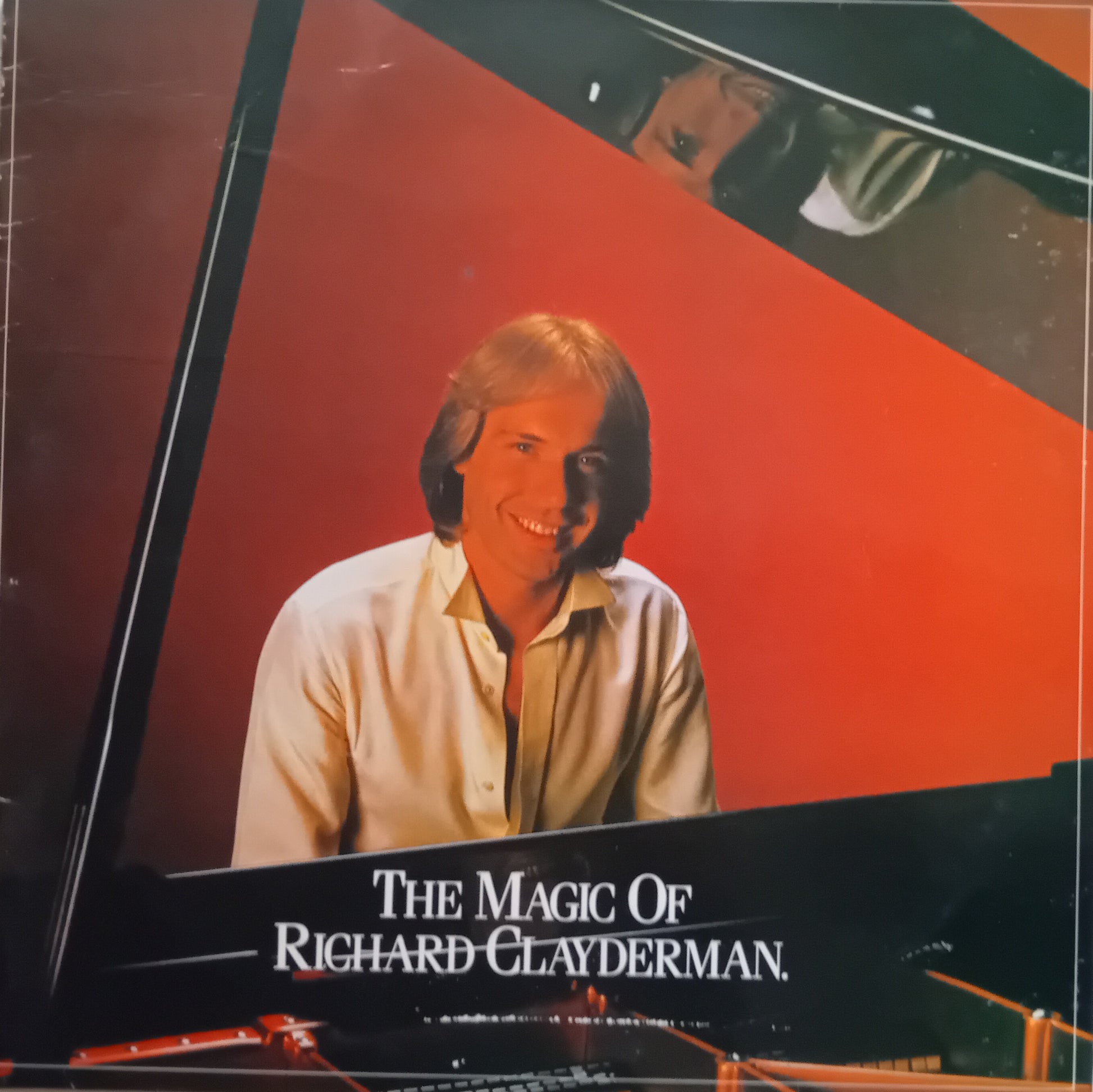 Album cover for 'The Magic of Richard Clayderman' featuring a smiling Richard Clayderman in front of a red and black geometric background.
