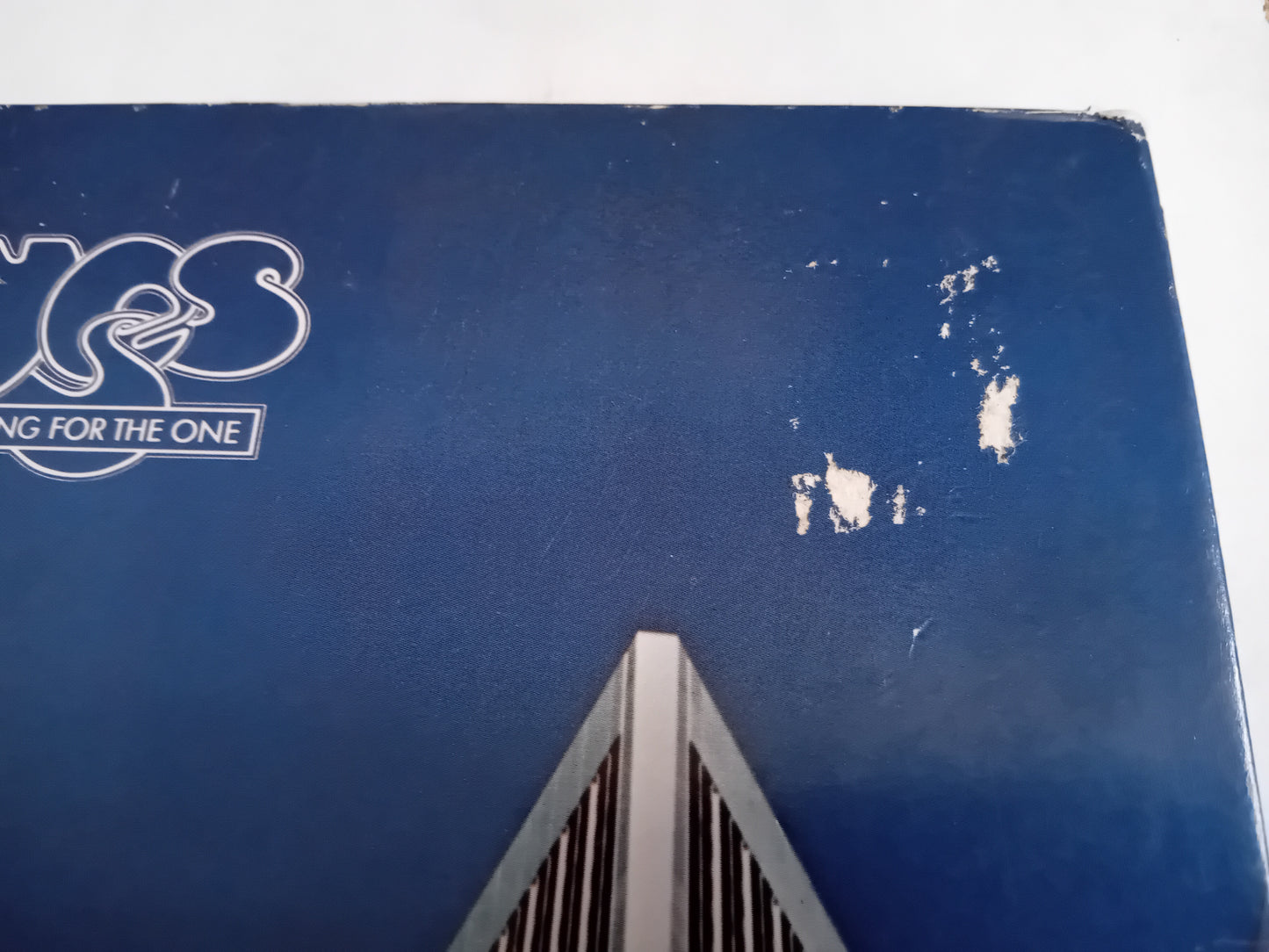 A close-up of a blue sleeve with a worn logo on the left and small surface tears.