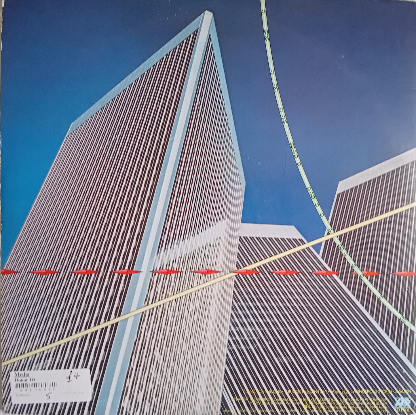 Rear cover depicting a low-angle view of modern skyscrapers against a blue sky, overlaid with colored geometric lines and a small white label in the bottom-left corner.