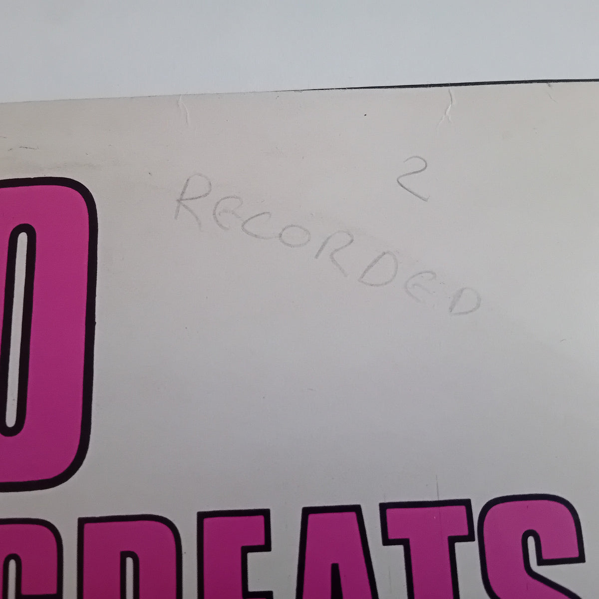 A close-up of a printed surface with large pink lettering and handwritten text reading 'RECORDED' with the number 2 above it.