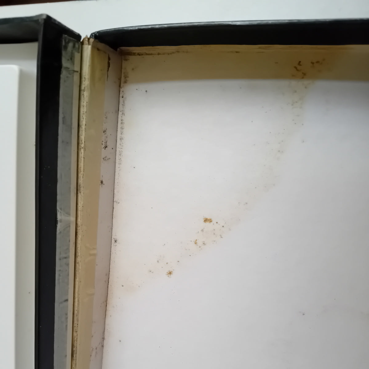 Close-up of the inside corner of a white rectangular box, showing a worn beige inner lining and some brown staining or scuffing near the top edge.
