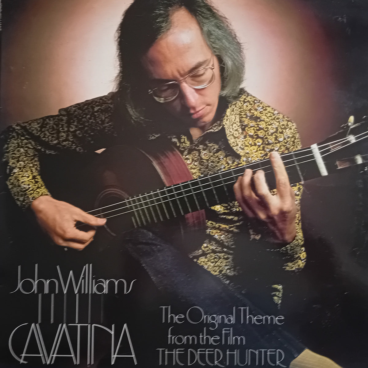 Album cover for 'The Original Theme from the Film The Deer Hunter' by John Williams and Cinematographer Michael Catena, featuring a portrait of John Williams playing an acoustic guitar.