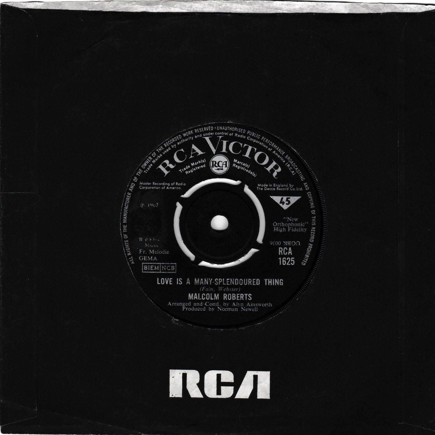 A black vinyl record partially pulled from its black paper sleeve, showing the RCA Victor label with the song title 'Love Is A Many Splendored Thing' by Malcolm Roberts and the RCA logo printed at the bottom of the sleeve.