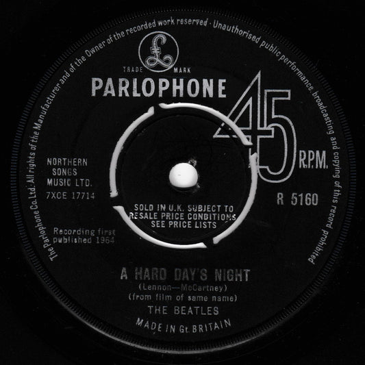 A close-up of a vintage Parlophone 45 RPM vinyl record label for The Beatles' 'A Hard Day's Night'. The black label features white text and a white center spindle area, with the Parlophone logo and catalog number R 5160 clearly visible.