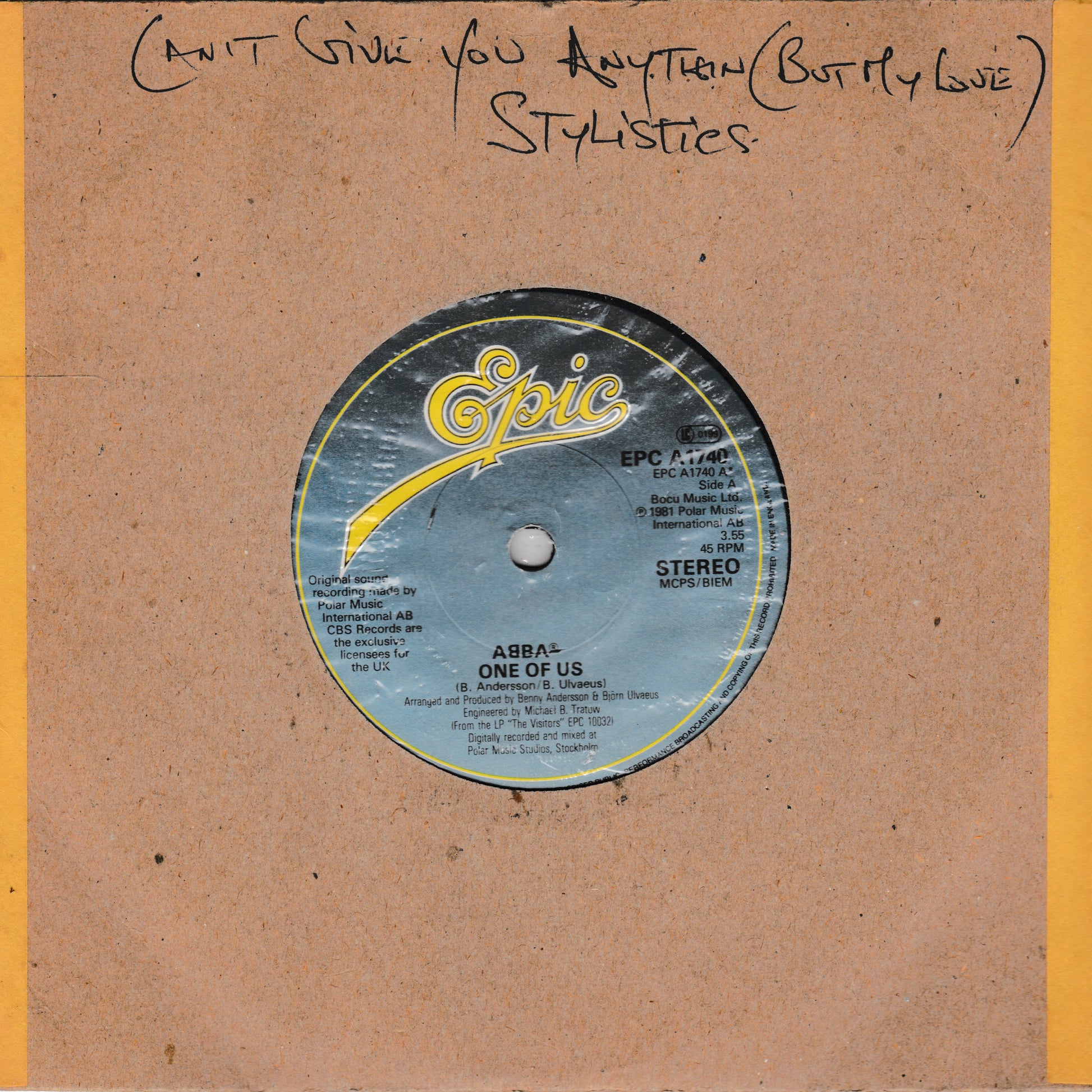 A vintage 7-inch vinyl record sleeve for ABBA's 'One of Us' on the Epic label, featuring a brown cardboard-style cover with a yellow stripe on the right and handwritten text at the top reading 'Can't Give You Anything Butty Love' and 'STYLISTICS'. The central label is blue with yellow and white details.