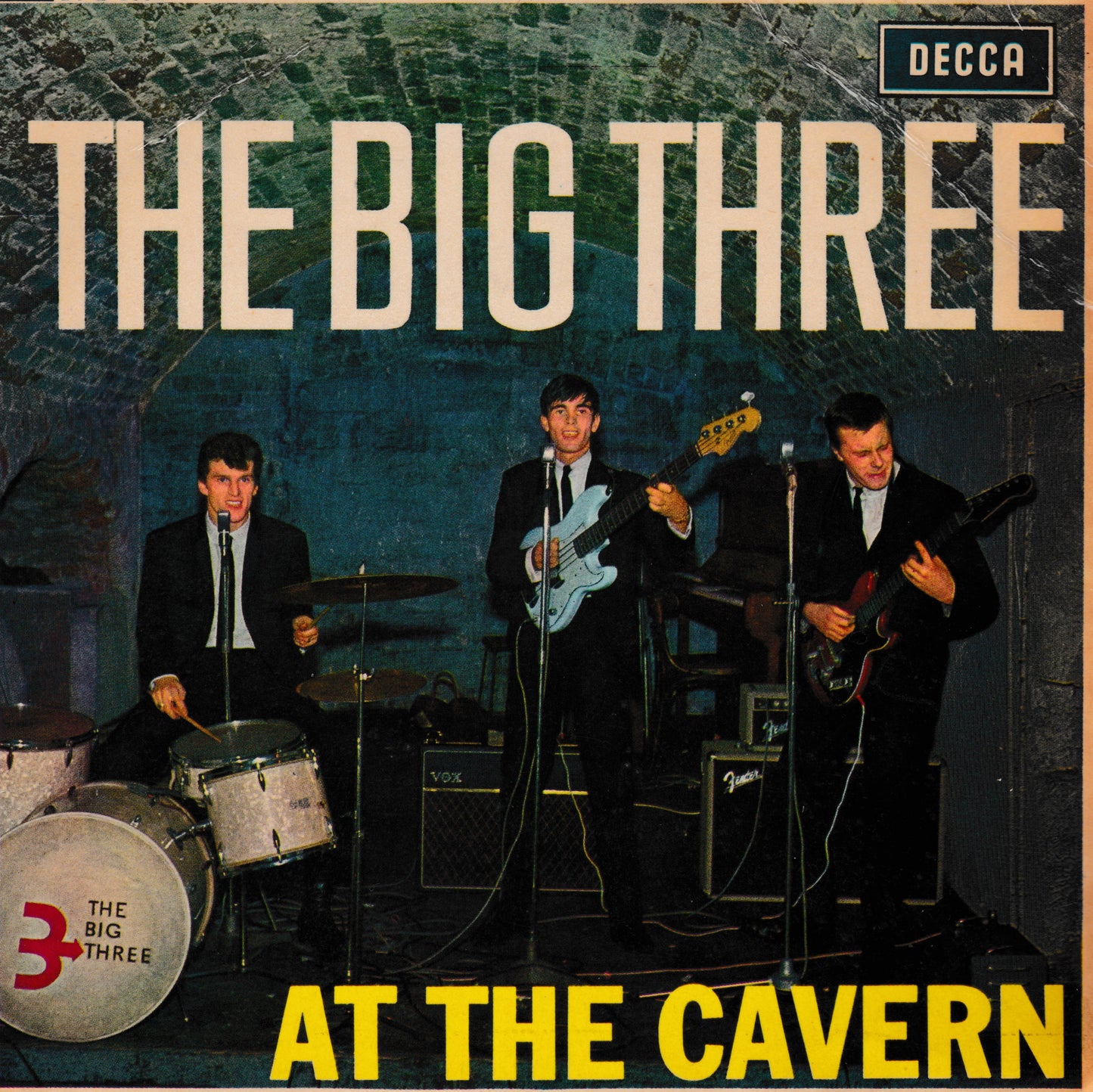 The Big Three 'At the Cavern' EP cover, featuring a band performing in a dark cavern. The text 'THE BIG THREE' appears at the top and 'AT THE CAVERN' at the bottom, with the Decca logo in the upper right corner.