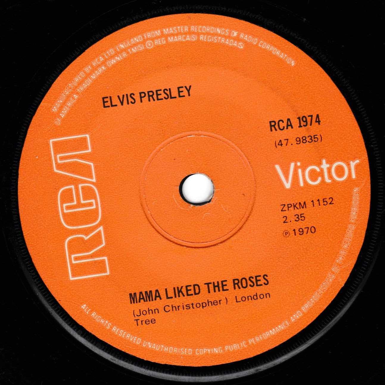 A close-up of a vintage vinyl record label for Elvis Presley's 'Mama Liked the Roses', featuring a bright orange centre label with white text and the RCA Victor logo on a black vinyl background.
