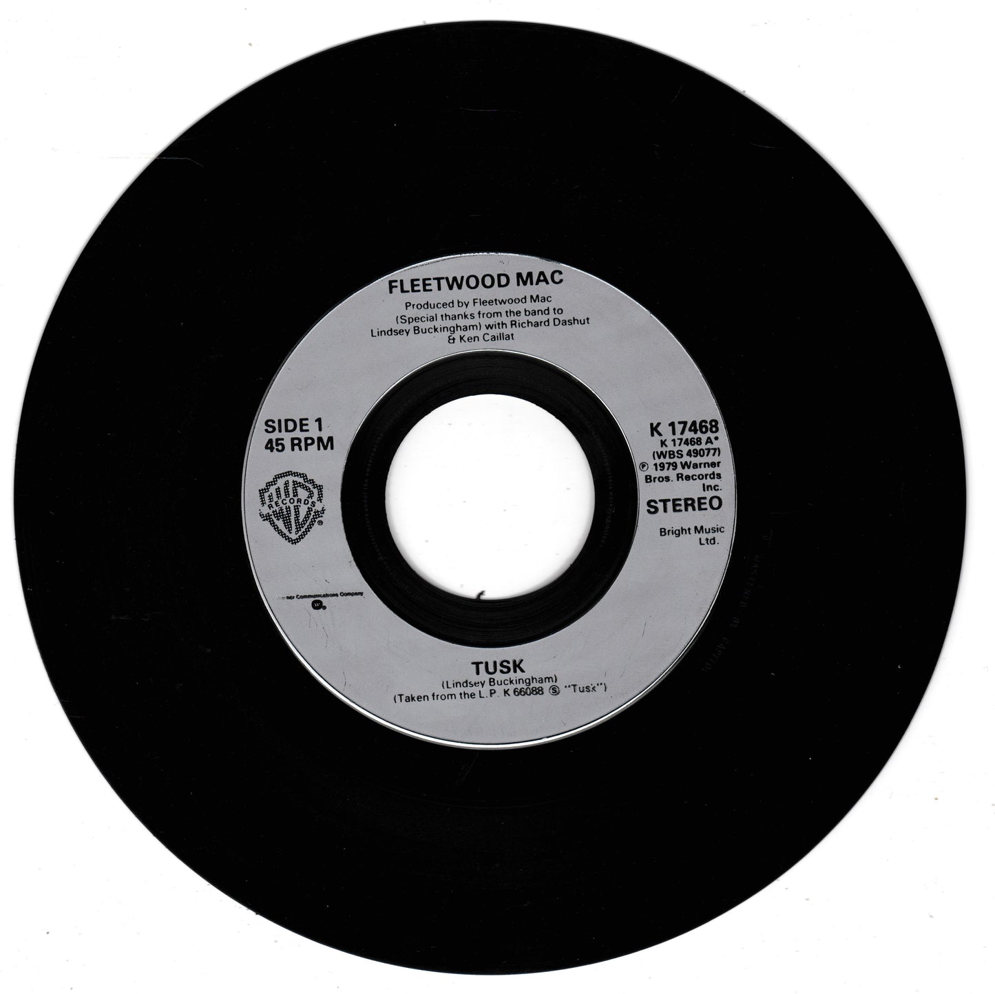 A black vinyl record label for Fleetwood Mac's song 'Tusk', featuring the Warner Bros. logo and 45 RPM and Stereo print details on a white background.