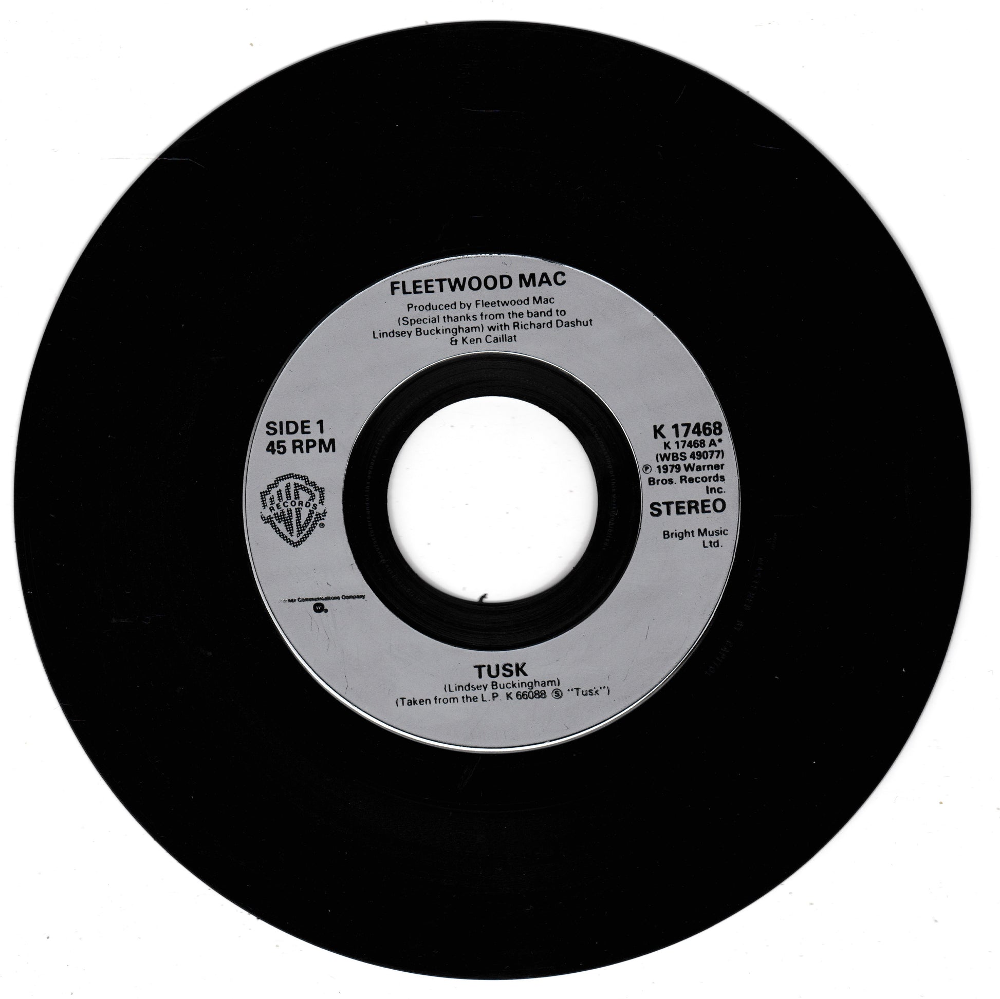 A black vinyl record label for Fleetwood Mac's song 'Tusk', featuring the Warner Bros. logo and 45 RPM and Stereo print details on a white background.