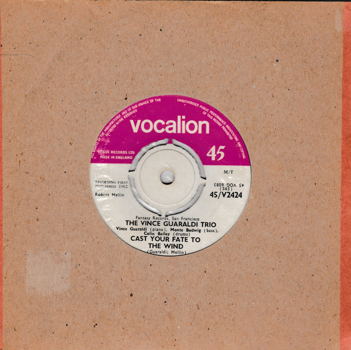 A 45 rpm vinyl record label for 'The Vince Guaraldi Trio - Cast Your Fate to the Wind' on Vocalion Records, set against a textured tan cardboard backing.