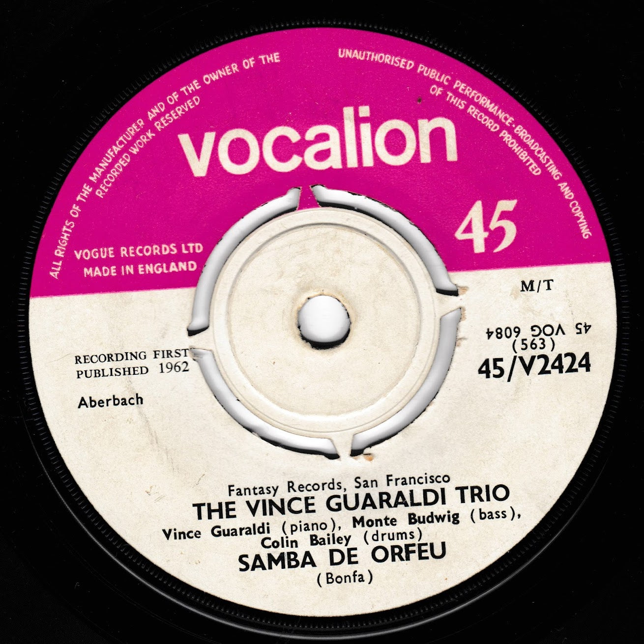 A close-up of a vinyl record label for 'Samba de Orfeu' by The Vince Guaraldi Trio, featuring a pink and cream-coloured Vocalion record cover on a black vinyl disc.