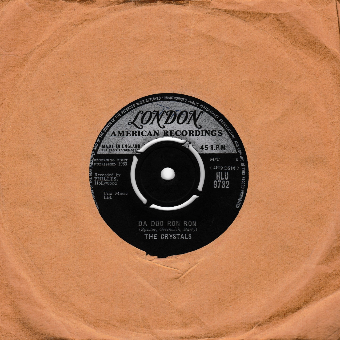 A vintage 45 RPM vinyl record from London American Recordings, featuring The Crystals' song 'Da Doo Ron Ron'. The black record label is centered on a square, textured tan paper sleeve.