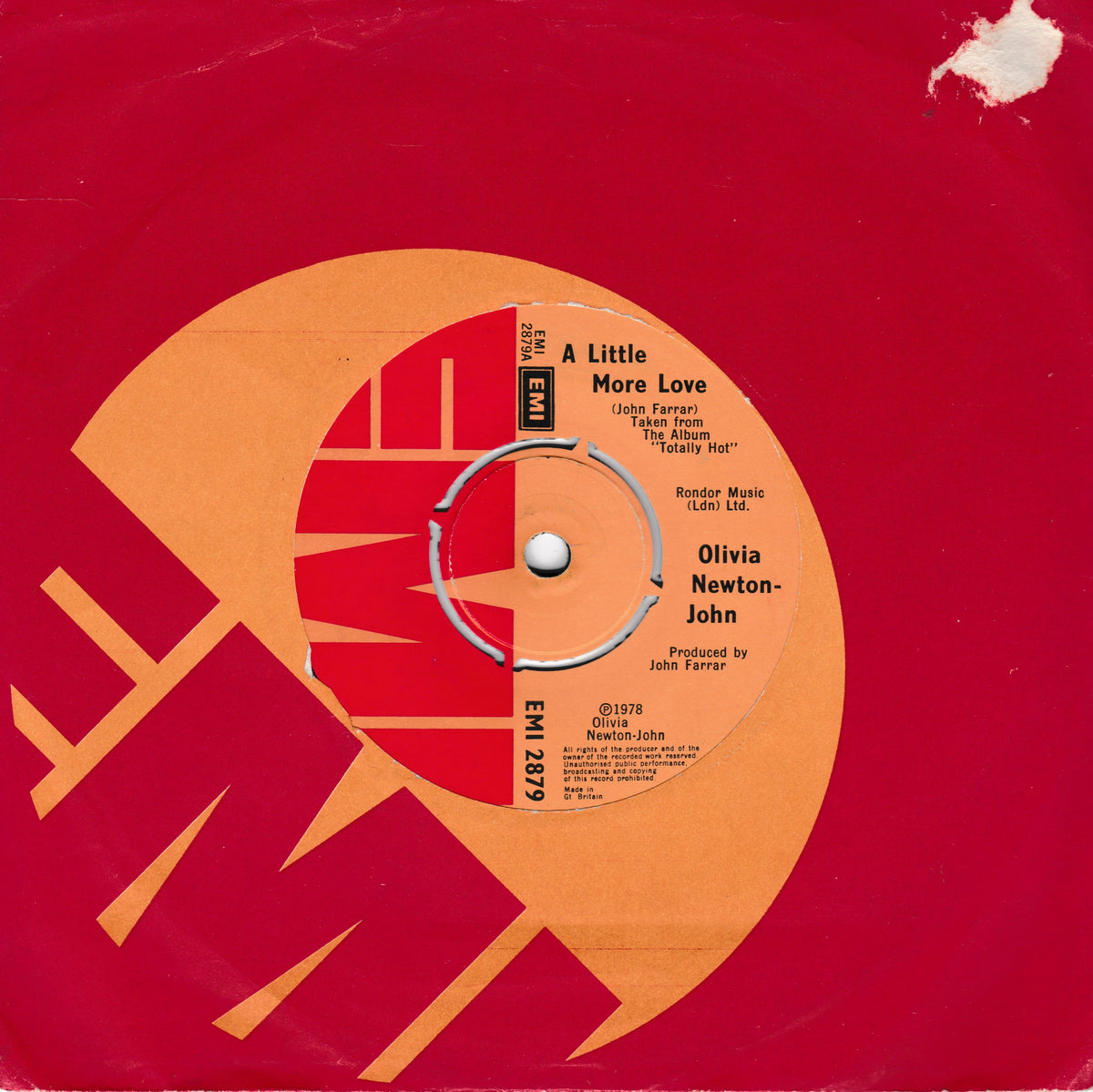 A vinyl record sleeve or inner label design with a bold red background, a large orange circular graphic, and printed text for Olivia Newton-John's song 'A Little More Love.' Visible text includes the artist name, album title, and EMI branding.