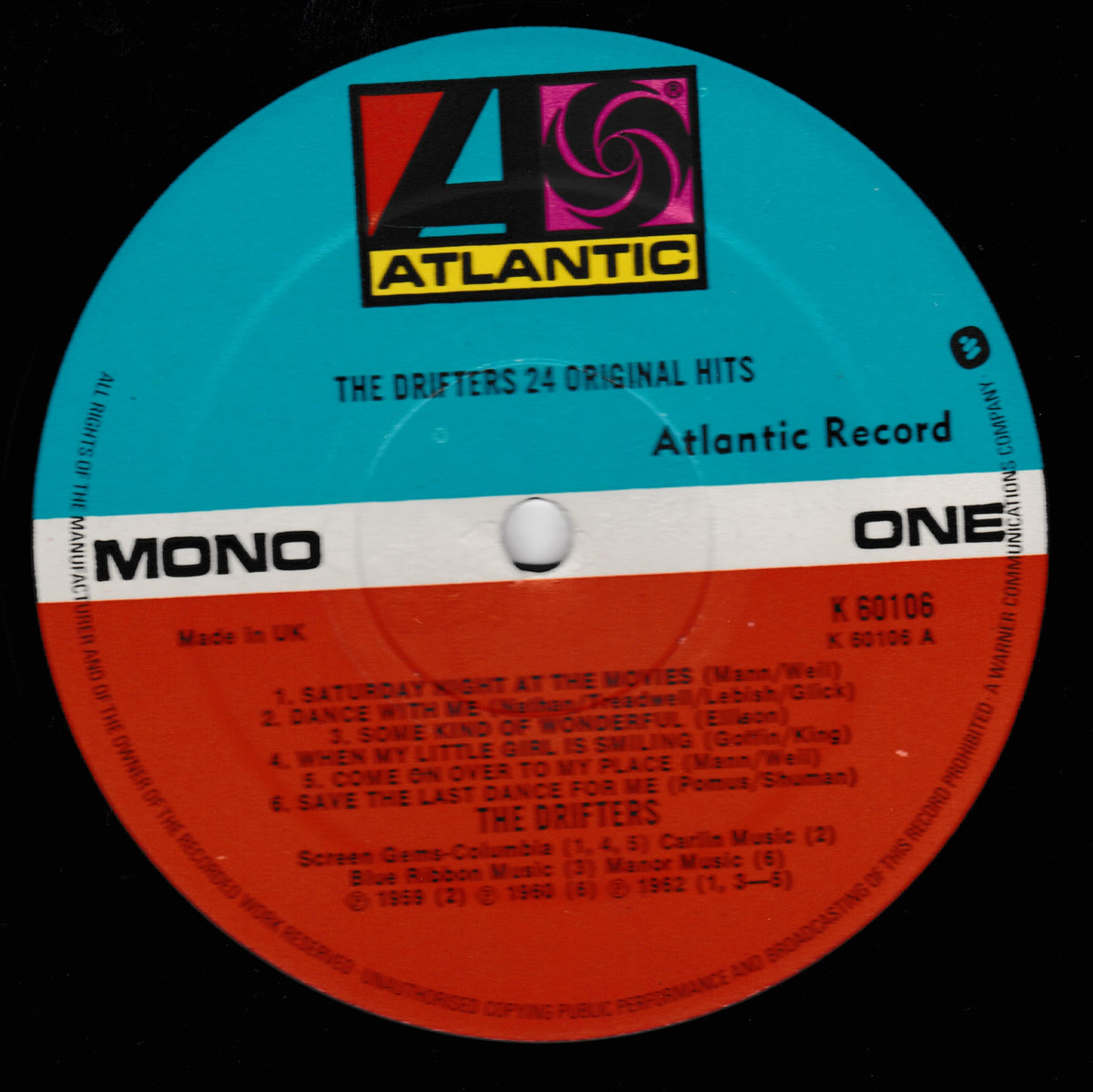 A close-up of a vinyl record label for Atlantic Records' 'The Drifters 24 Original Hits', featuring a bright blue outer ring, a white band with black text, and a red inner circle with track listings.