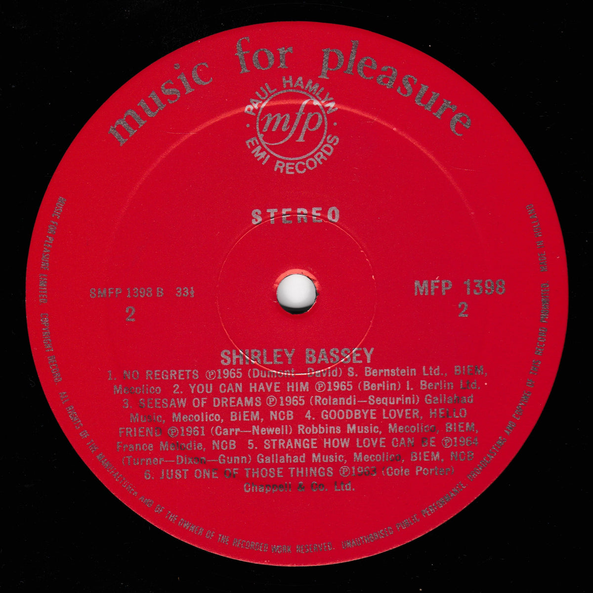 A red vinyl record label for Shirley Bassey on EMI Records, featuring white text and a central white hub, photographed against a black background.