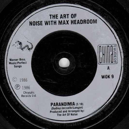 A close-up of a vinyl record label reading 'THE ART OF NOISE WITH MAX HEADROOM' and 'PARANOIMIA,' with Chrysalis Records branding and black-and-white contrast.