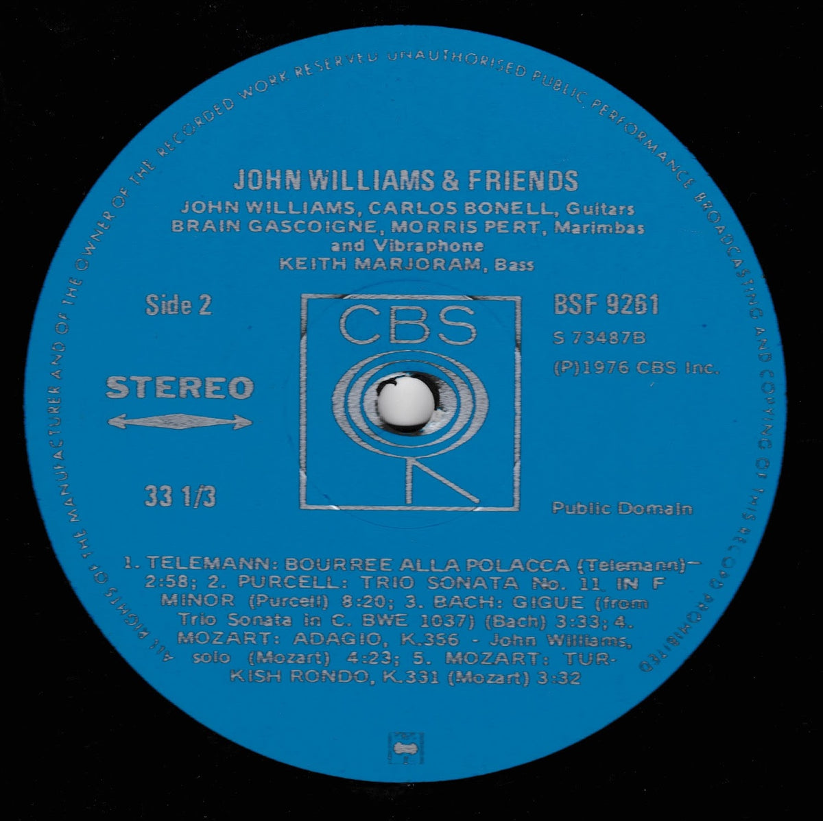 A blue vinyl record label with white text reading 'John Williams & Friends' and CBS branding, photographed against a black record surface.