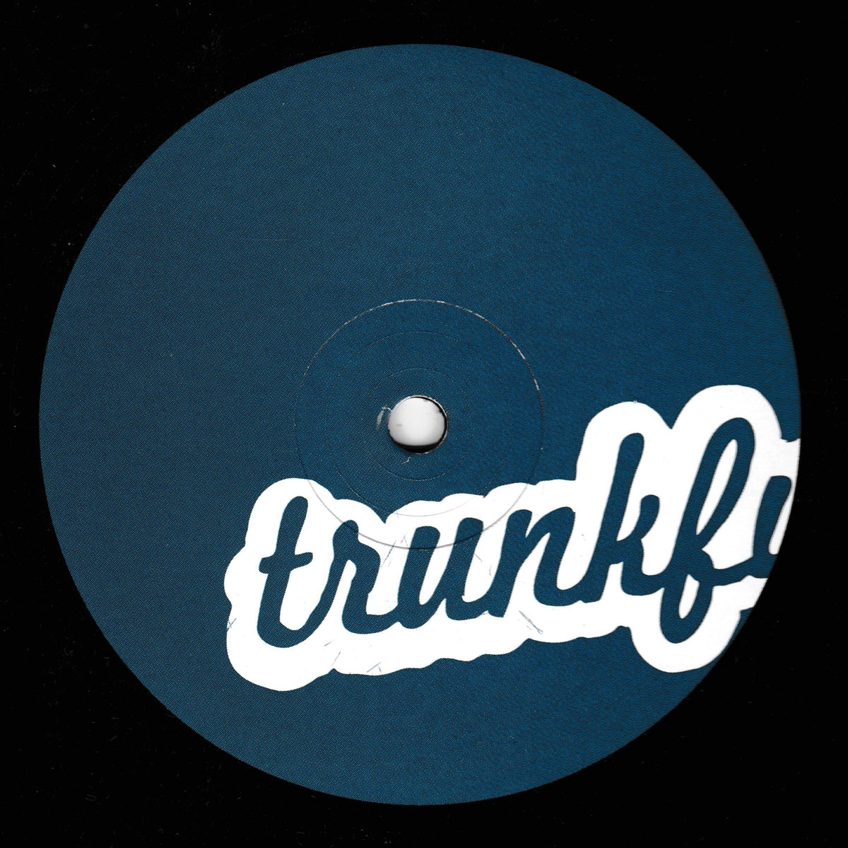 A circular dark blue vinyl record label with a white stylized 'trunkfu' logo across the lower half, photographed against a black background.
