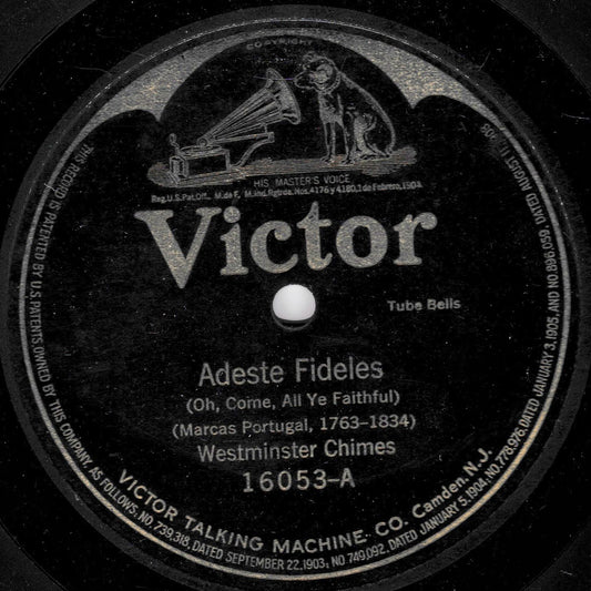 A close-up of a vintage Victor record label reading 'Adeste Fideles' with 'Westminster Chimes' and catalog number '16053-A'. The black circular label has white text and an illustration of a gramophone and dog near the top.