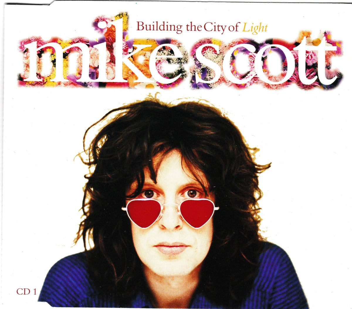 Single cover for Mike Scott's 'Building the City of Light' CD, featuring a portrait of the artist wearing red heart-shaped sunglasses against a white background with colorful stylized text.