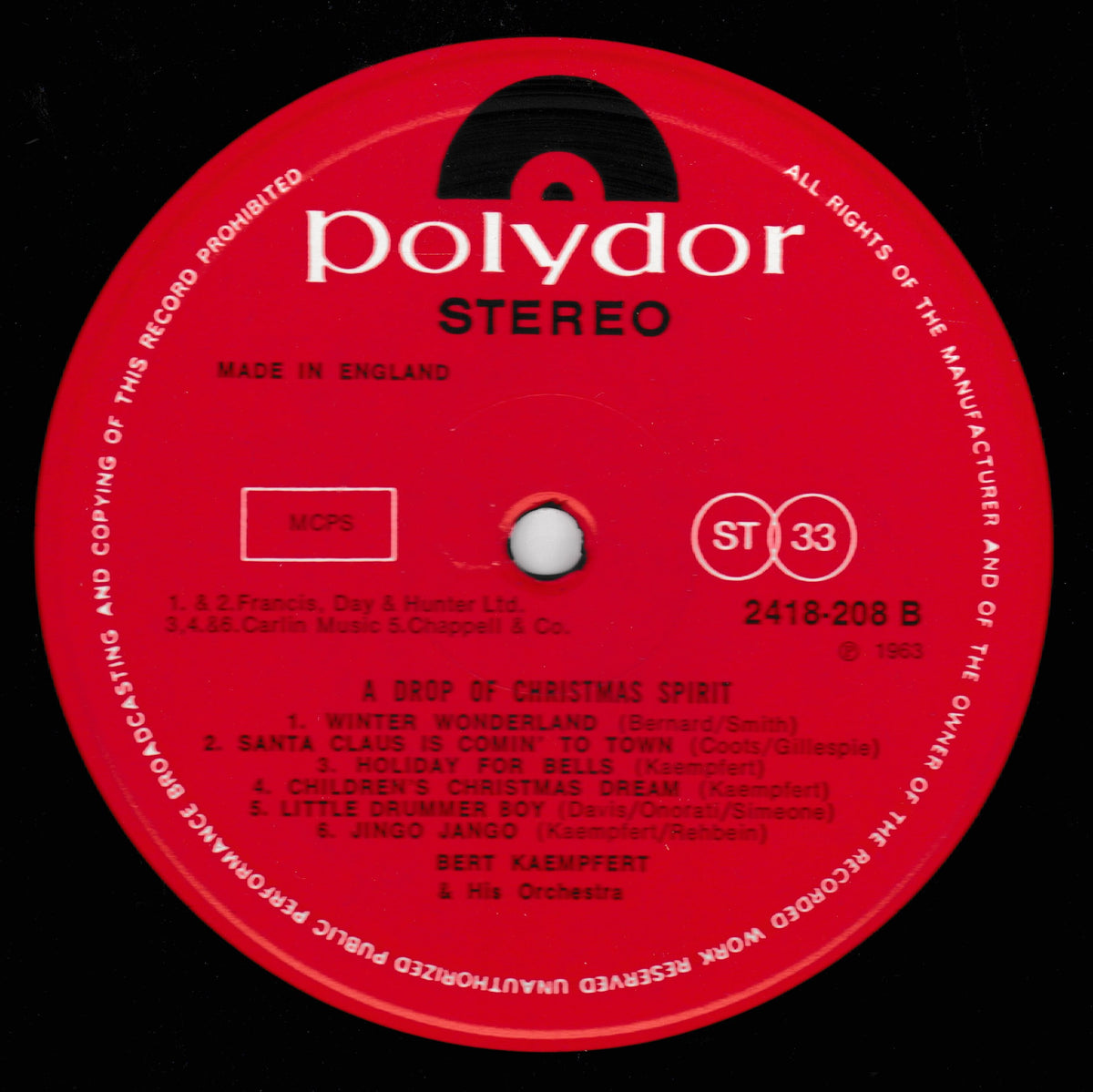 A close-up of a red Polydor Stereo record label with white printed text and track listing, featuring the title 'A Drop of Christmas Spirit' and artist Bert Kaempfert.