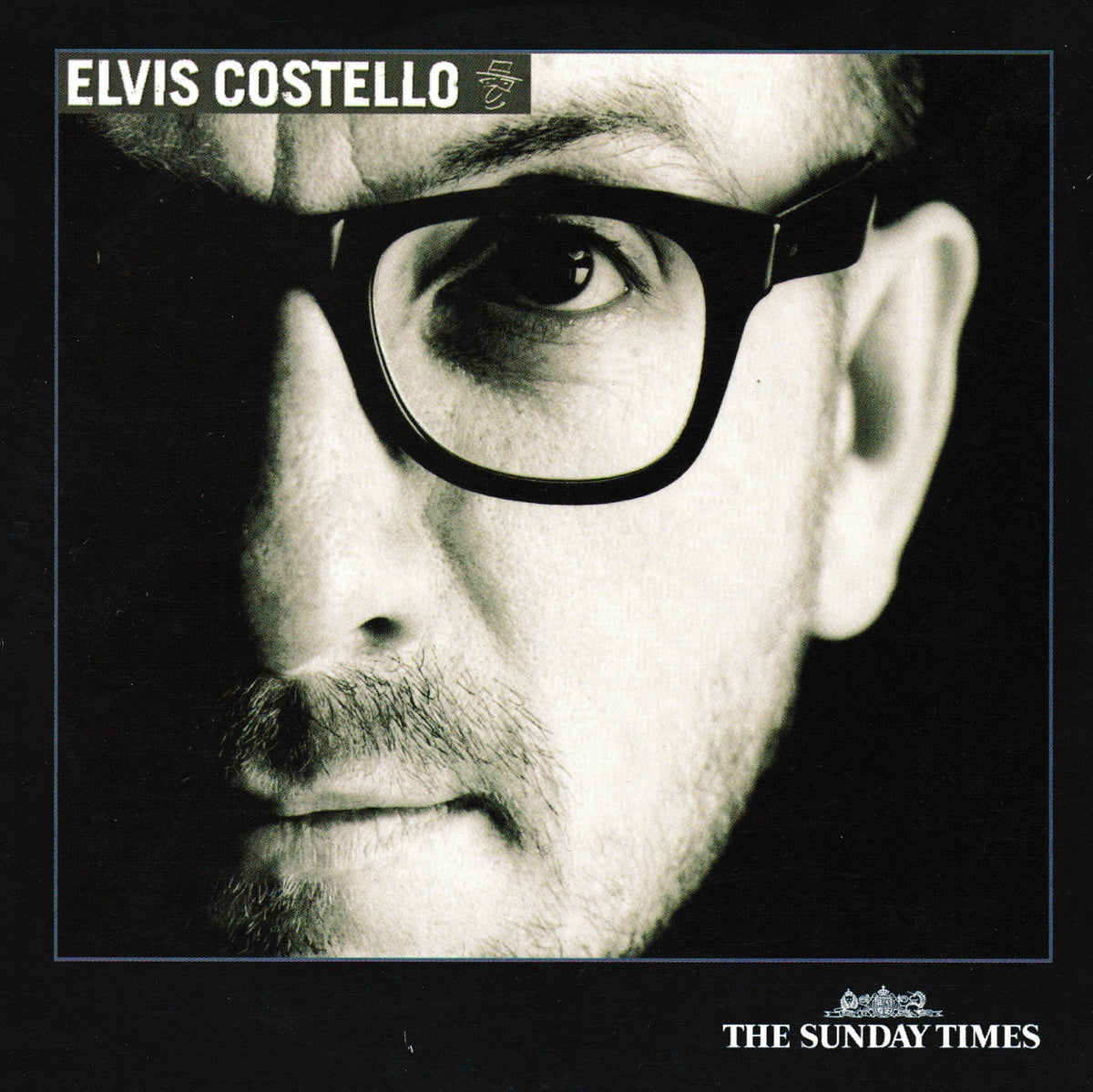 Album cover for Elvis Costello's 'The Sunday Times' featuring a high-contrast black and white close-up portrait of the artist wearing thick black-rimmed glasses against a dark background, with the text 'ELVIS COSTELLO' at the top and 'THE SUNDAY TIMES' at the bottom.