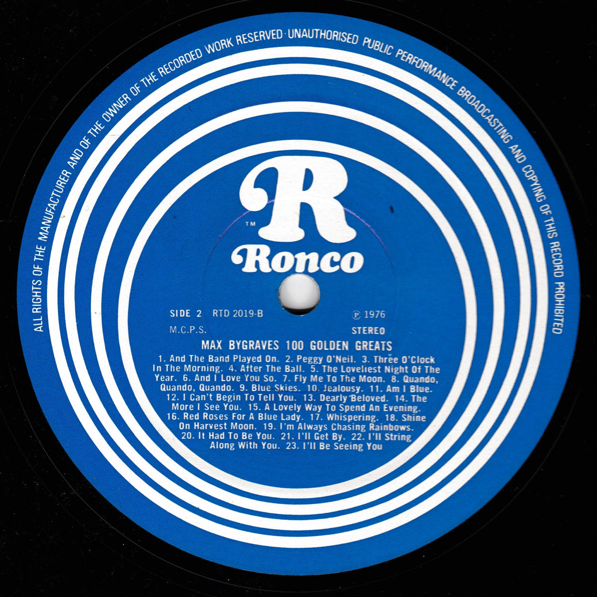 A close-up of a black vinyl record label with a bright blue centre label featuring the white Ronco logo and track listing text for Max Bygrave's '100 Golden Greats'.