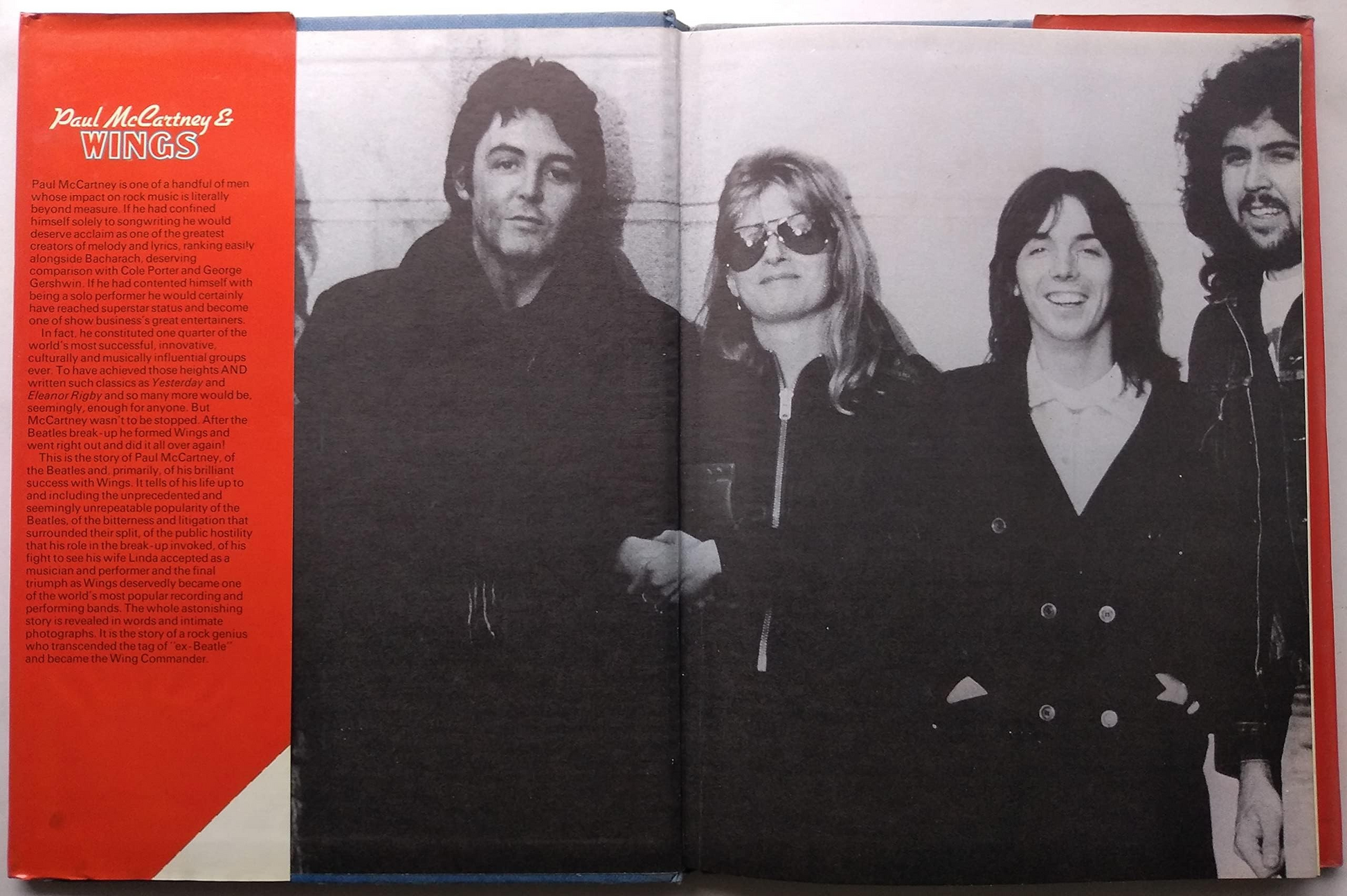 An open printed book page showing a black-and-white group portrait of four people, with a red left margin containing text and the title 'Paul McCartney & Wings'.